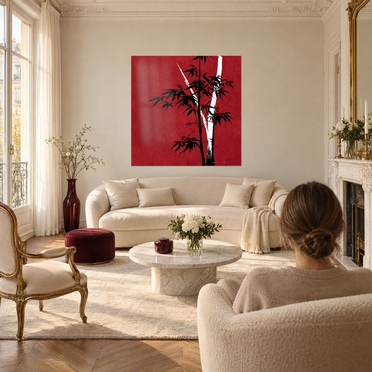 Quadro steli di bambù neri su fondo rosso carminio, stelo bianco a V, donna di spalle, sopra un divano in un soggiorno luminoso