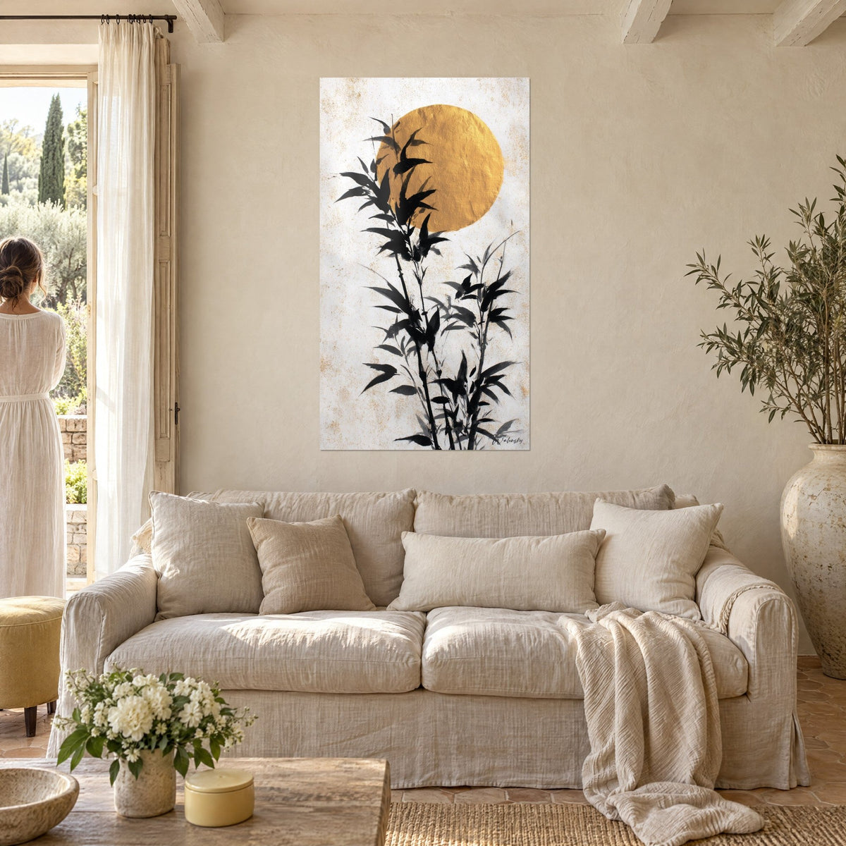 Tableau tiges de bambou à l'encre noire devant un disque d'or martelé sur fond crème, au-dessus d'un canapé dans un salon lumineux