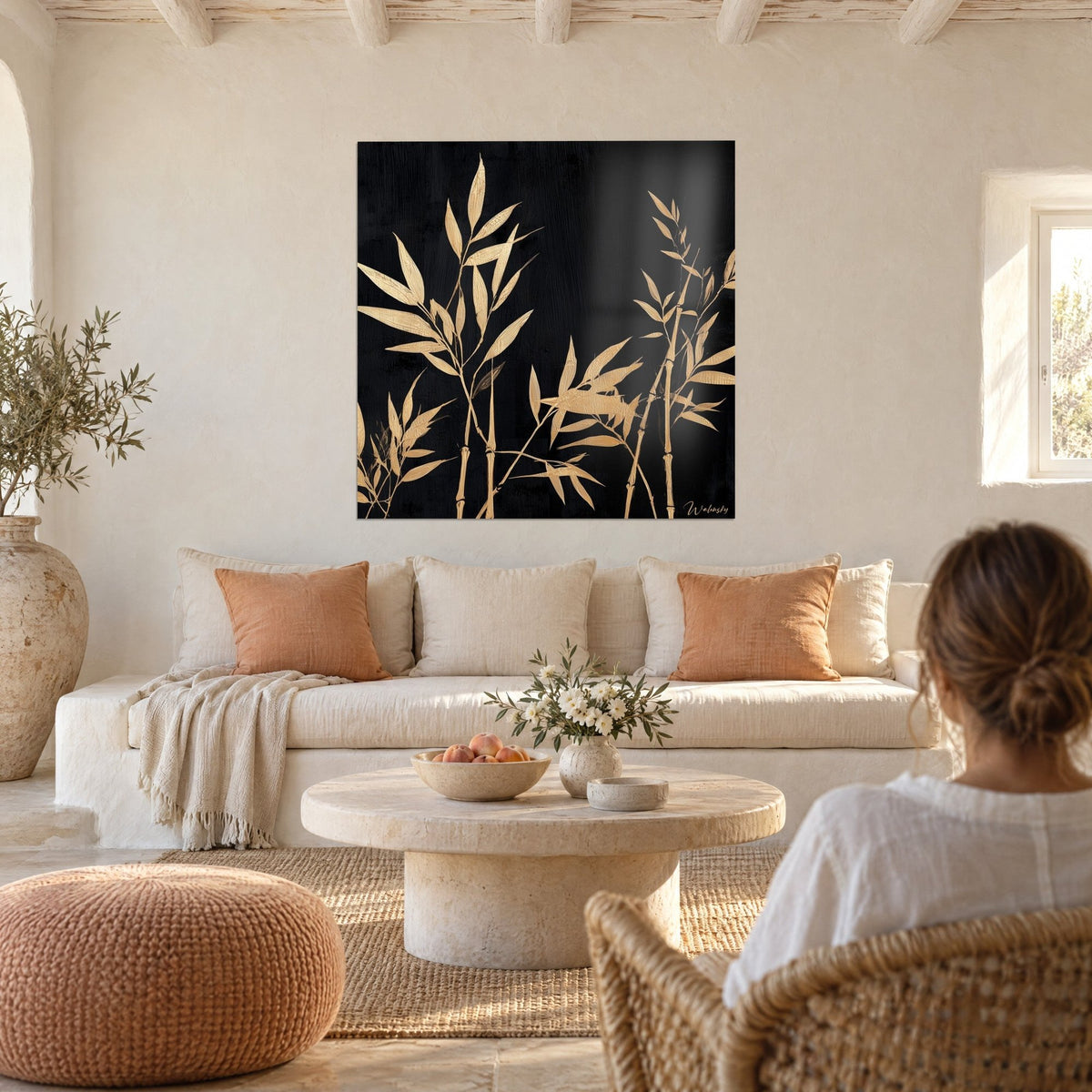 Tableau bambous dorés se détachant sur fond noir mat, murs blanc crème et coussins abricot, au-dessus d'un canapé dans un salon lumineux