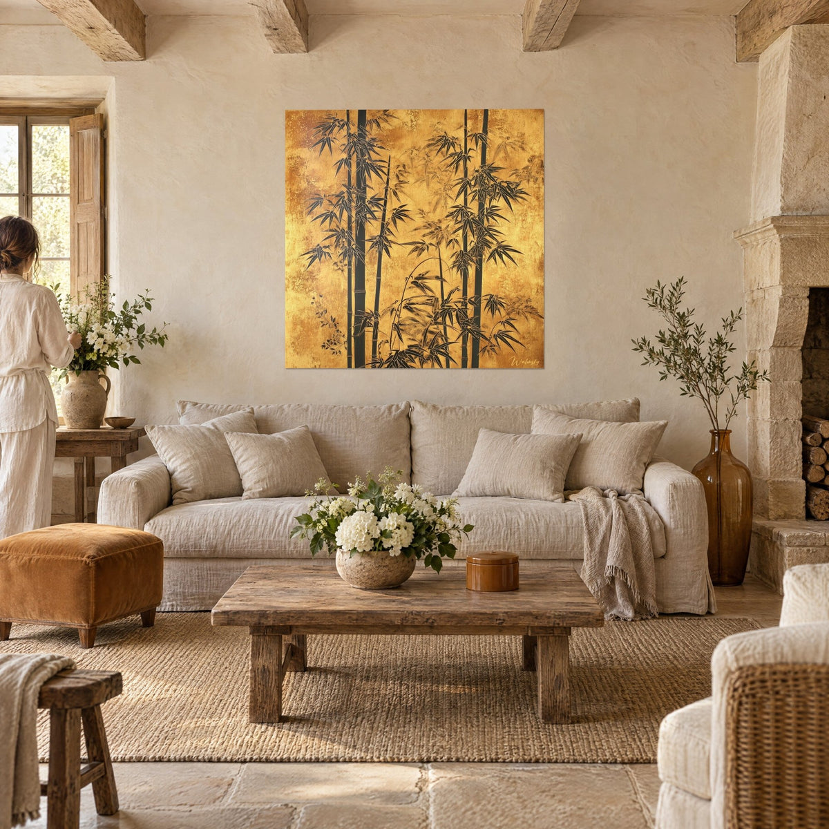 Tableau bambous noirs sur fond or patiné, feuilles effilées et ocre cuivré, vu par deux personnes au-dessus d'un canapé dans un salon lumineux