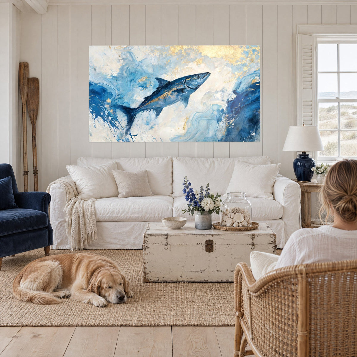 Gemälde Barrakuda in kobaltblau, springend, silbrige Schuppen und goldene Lichtreflexe, ein liegender Retriever, über einem Sofa in einem hellen Wohnzimmer