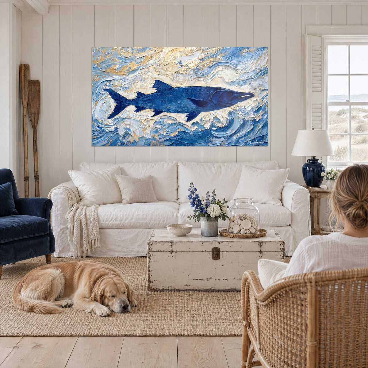 Wall art of a navy blue barracuda swimming through raised ivory waves, with a lying retriever, above a sofa in a bright living room