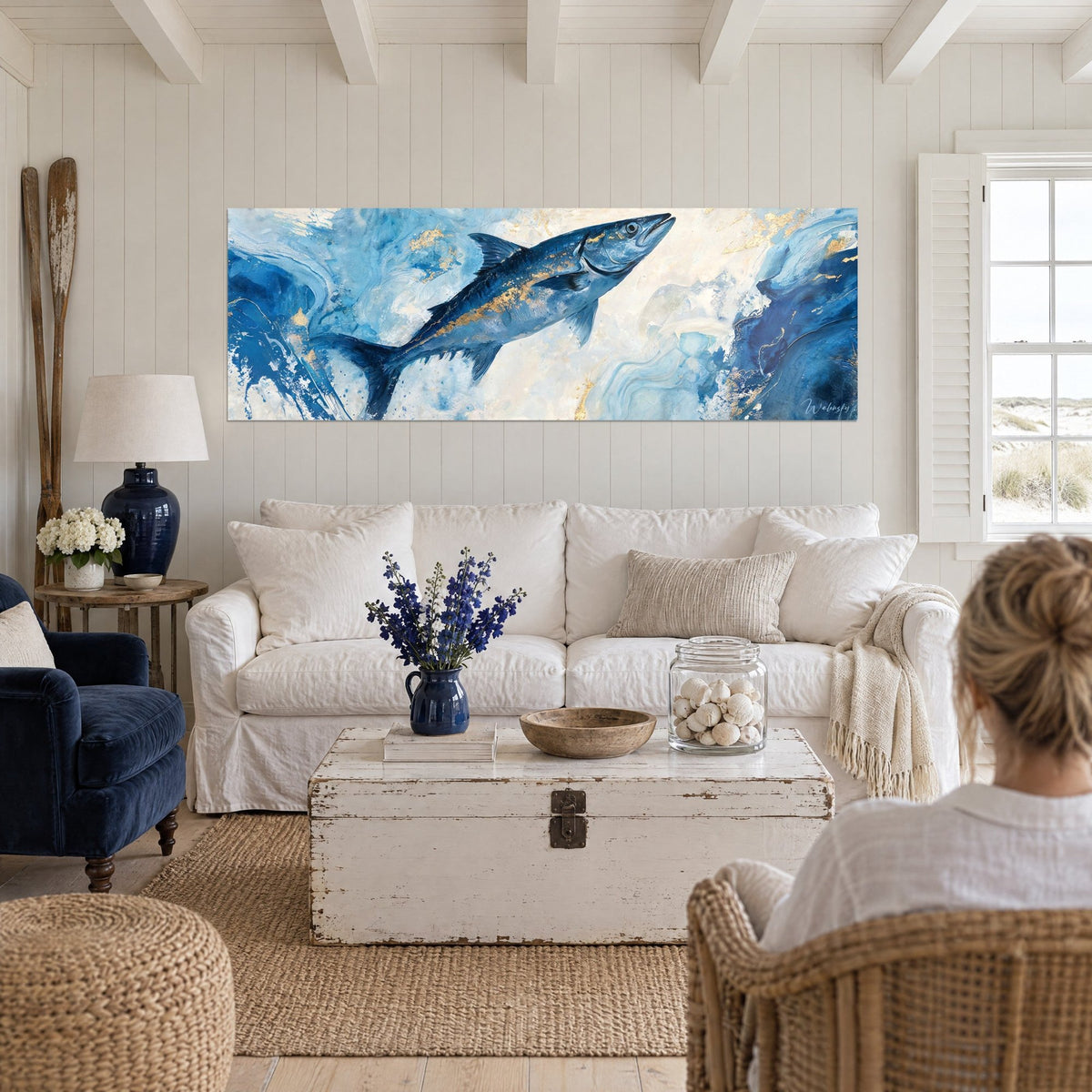 Wall art silver barracuda leaping, navy and gold on ivory foam, above a sofa in a bright living room