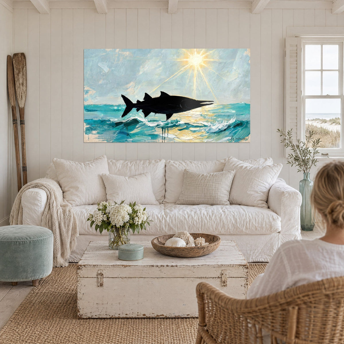 Wall art black barracuda leaping over turquoise waves, pale yellow sun shining above a sofa in a bright living room