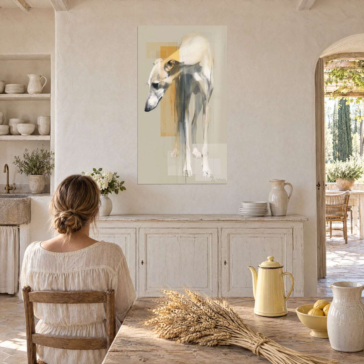 Quadro di un levriero dalle lunghe zampe grigie, dorso crema, linee sottili e tocchi dorati, cucina rustica di un mas in pietra