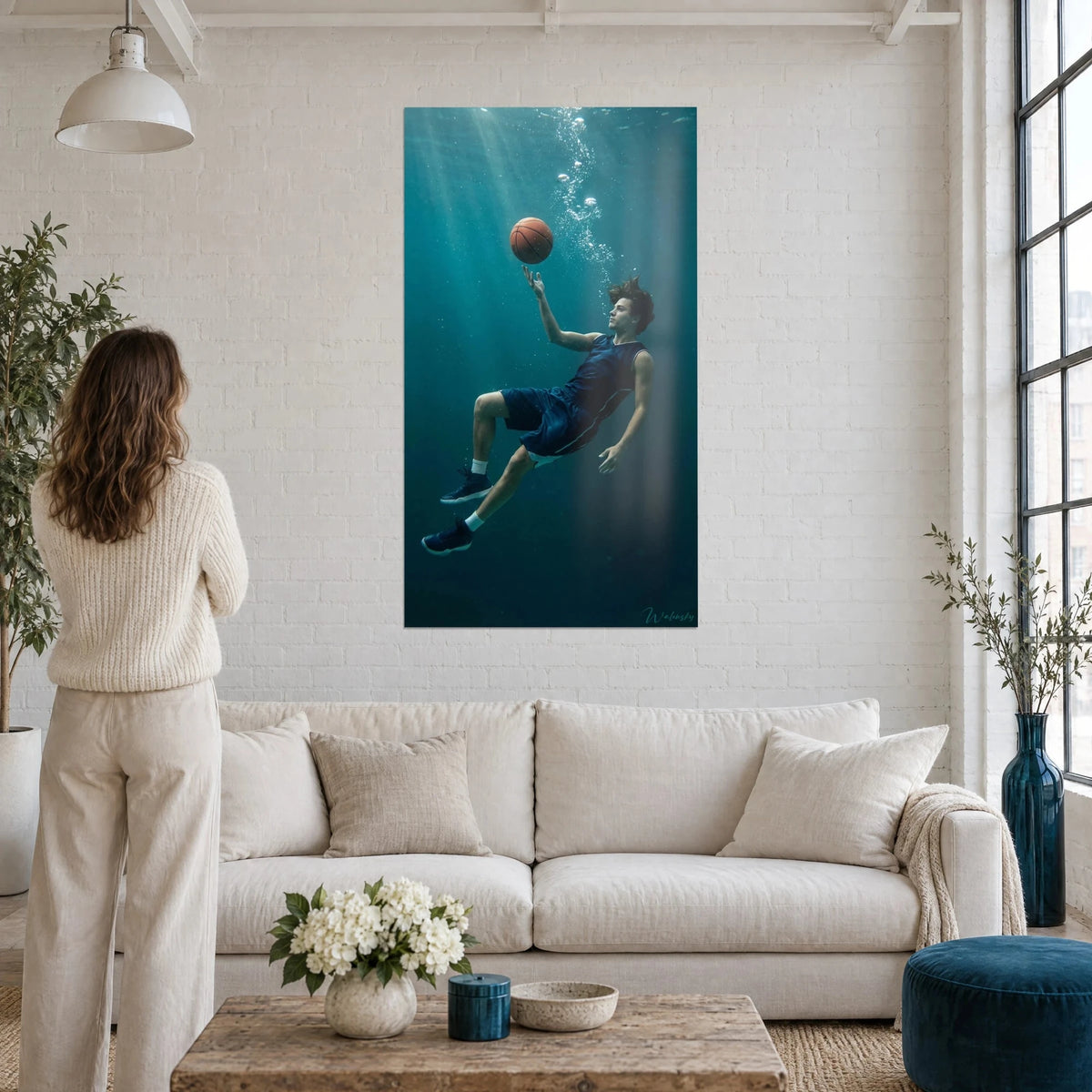 Schilderij van een zwevende basketballer in marineblauw shirt onder turquoise water, oranje bal in de lucht, boven een bank in een lichte woonkamer