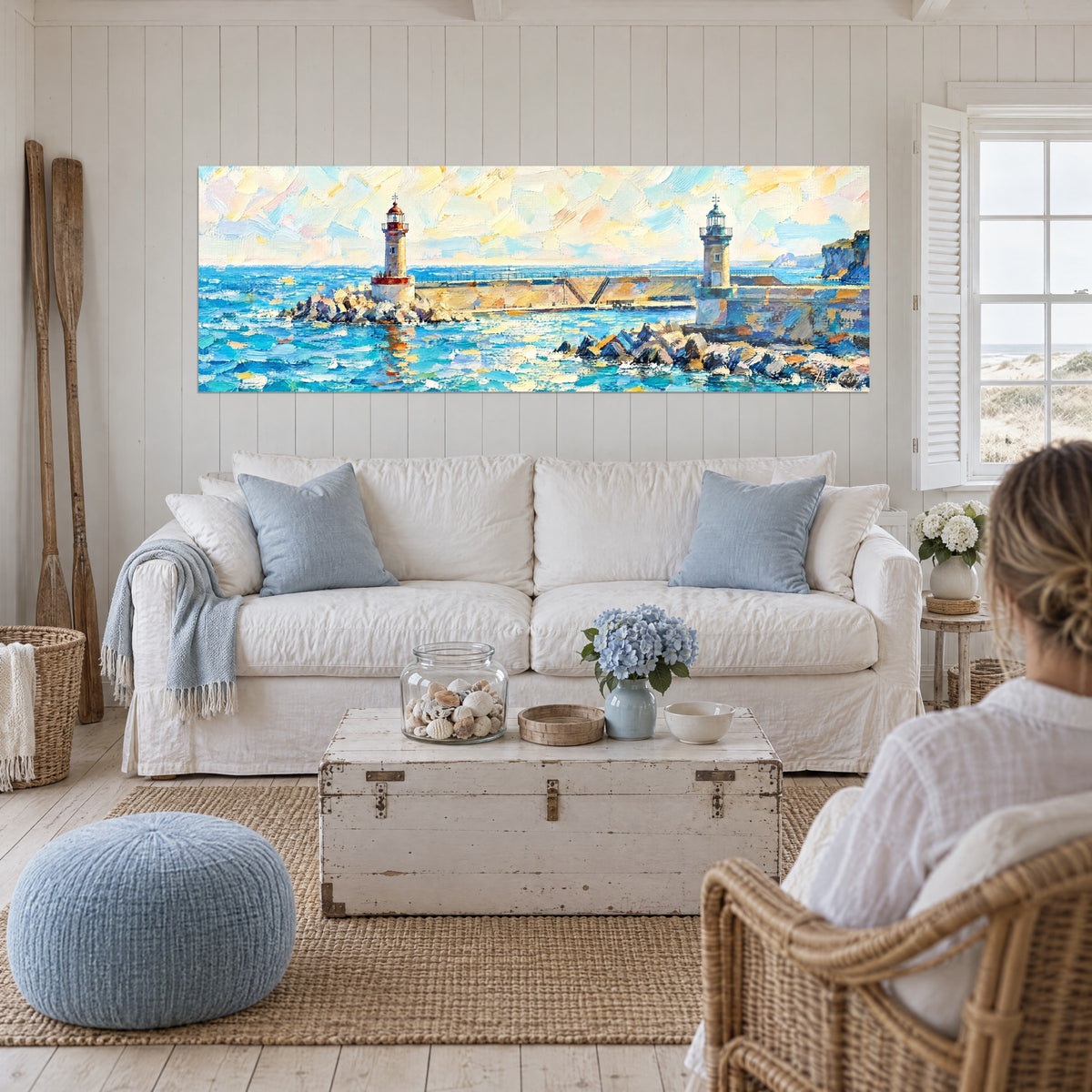 Wall art red-domed lighthouse on a rocky jetty, turquoise sea and golden sky, above a sofa in a bright living room