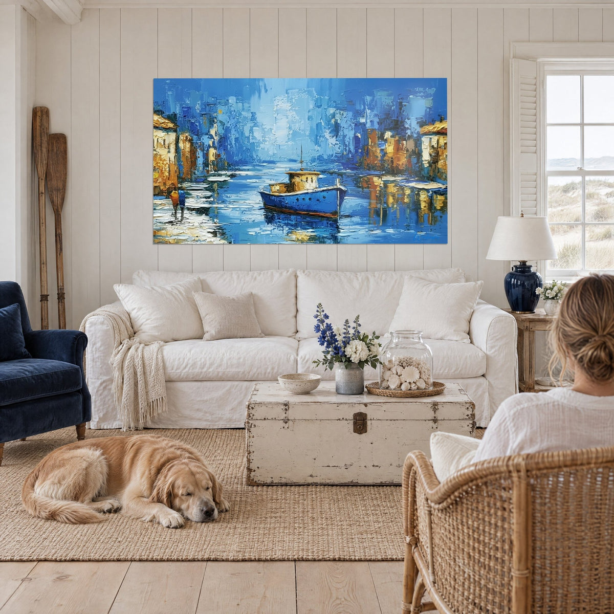 Tableau barque bleu cobalt à cabine ocre sur un canal, façades dorées et reflets nacrés, retriever couché, au-dessus d'un canapé dans un salon lumineux
