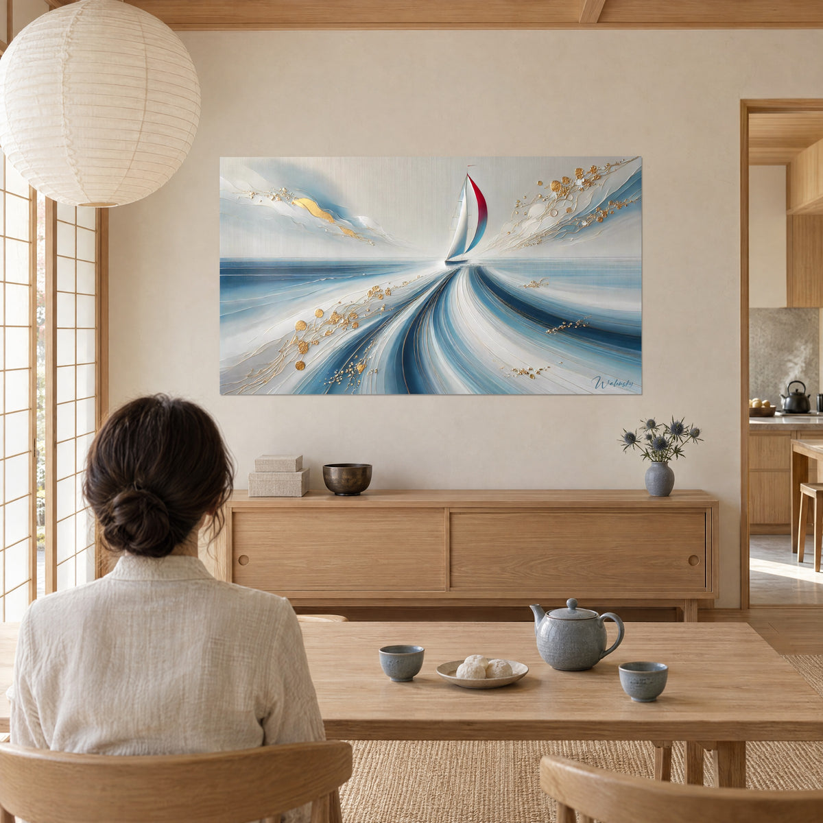 Quadro barca a vela rossa che taglia una scia blu ghiacciaio e bianca, dorature in rilievo, donna di spalle al tavolo, soggiorno japandi