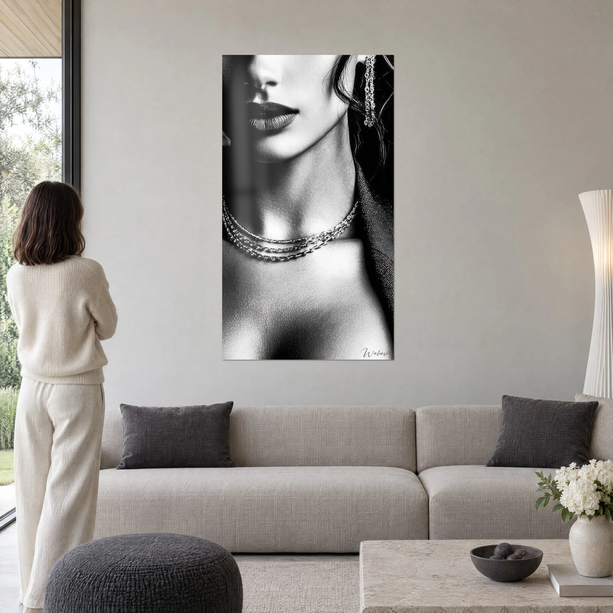 Wall art black and white female portrait, dark lips and triple silver necklace, above a sofa in a bright living room