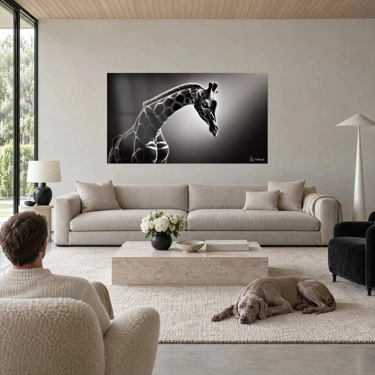 Tableau girafe au cou arqué, robe noire et blanche sur fond gris, regard baissé, au-dessus d'un canapé dans un salon lumineux