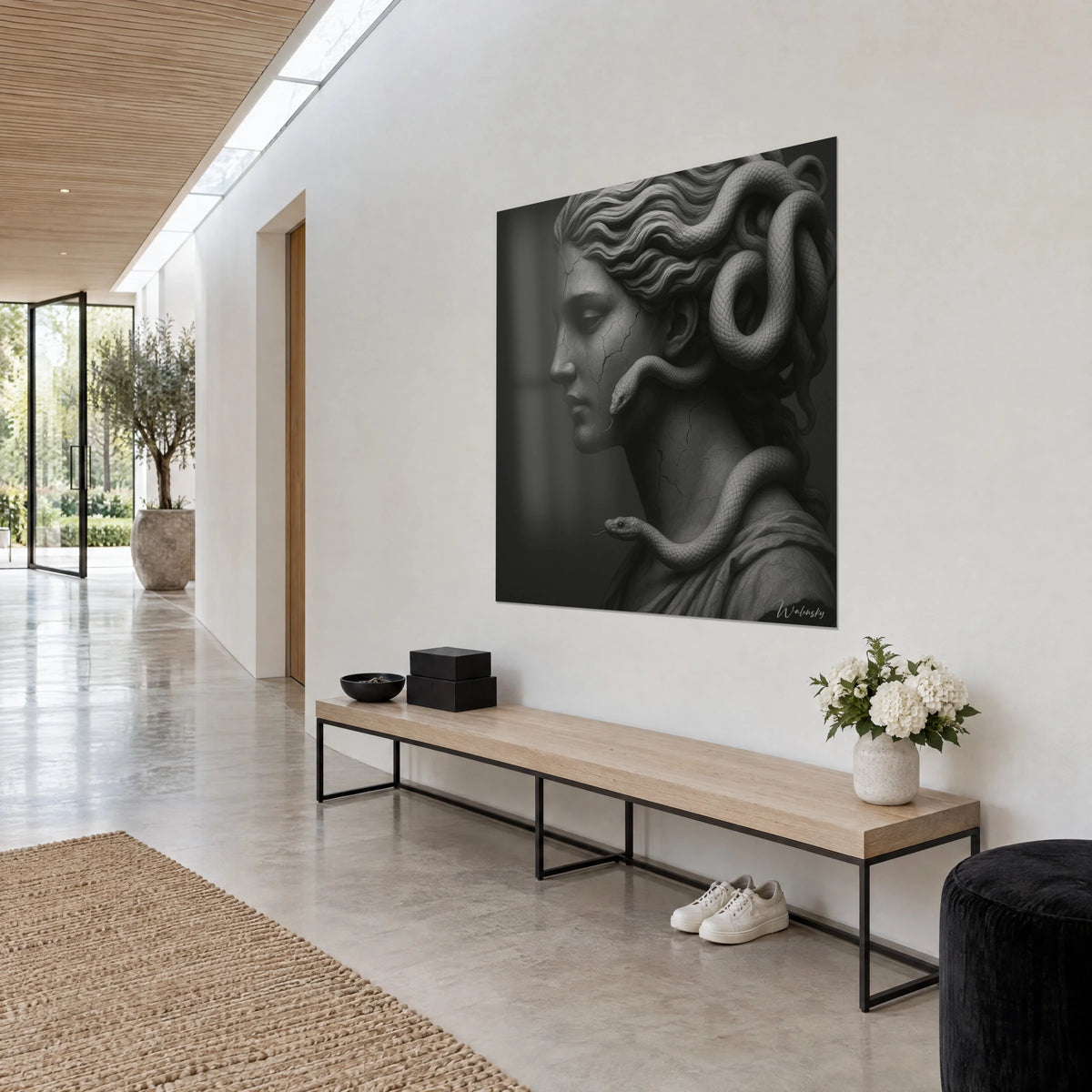 Wall art Medusa in grey marble, cracked face and pale snake on the shoulder, hung in a white and light wood hallway