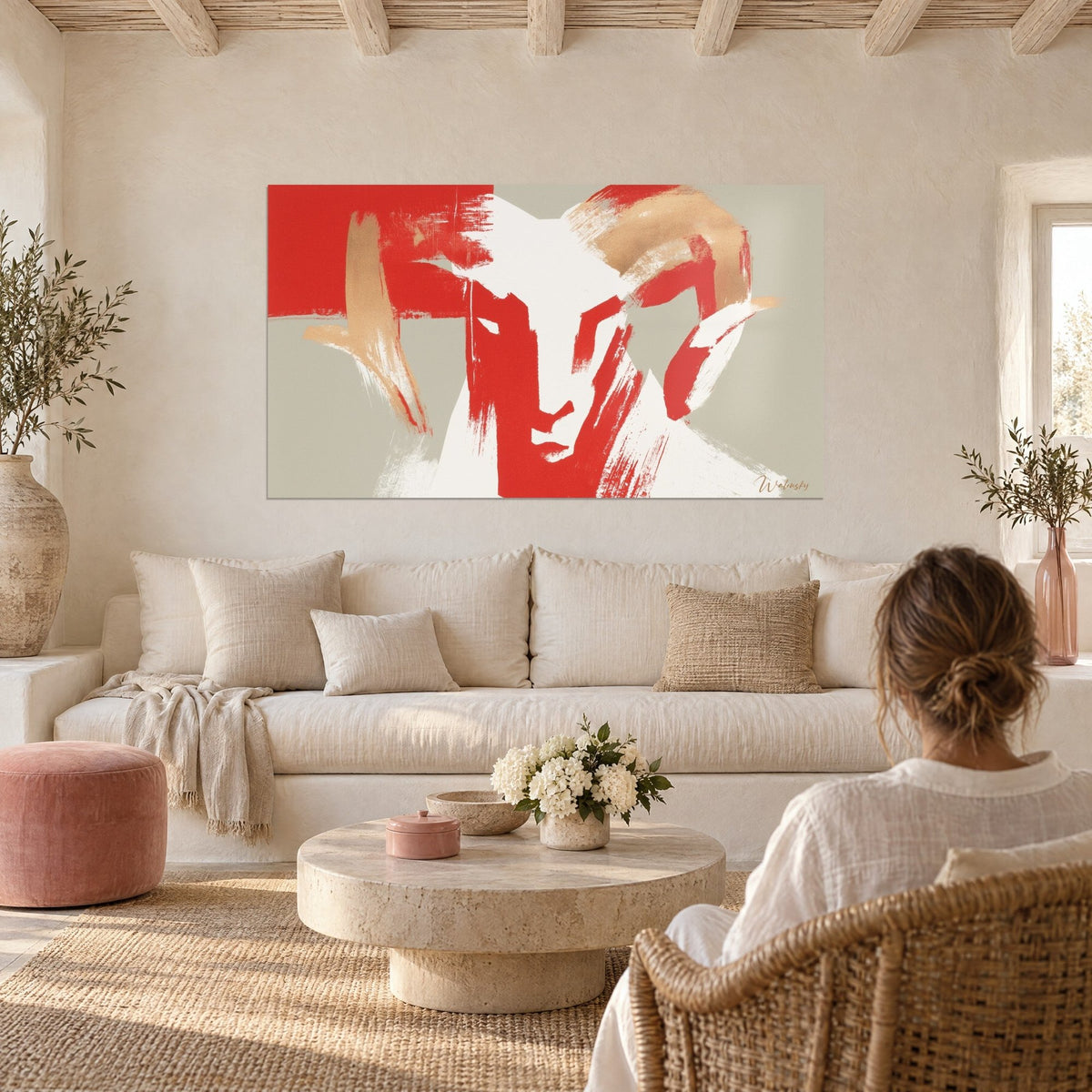 Tableau bélier stylisé aux traits rouges vifs et cornes beige doré, au-dessus d'un canapé dans un salon lumineux
