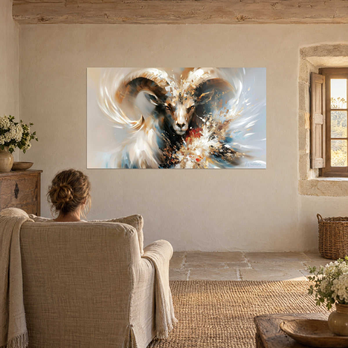 Wall art wild sheep with large brown horns, gold dust and navy blue, woman seen from behind in a linen armchair