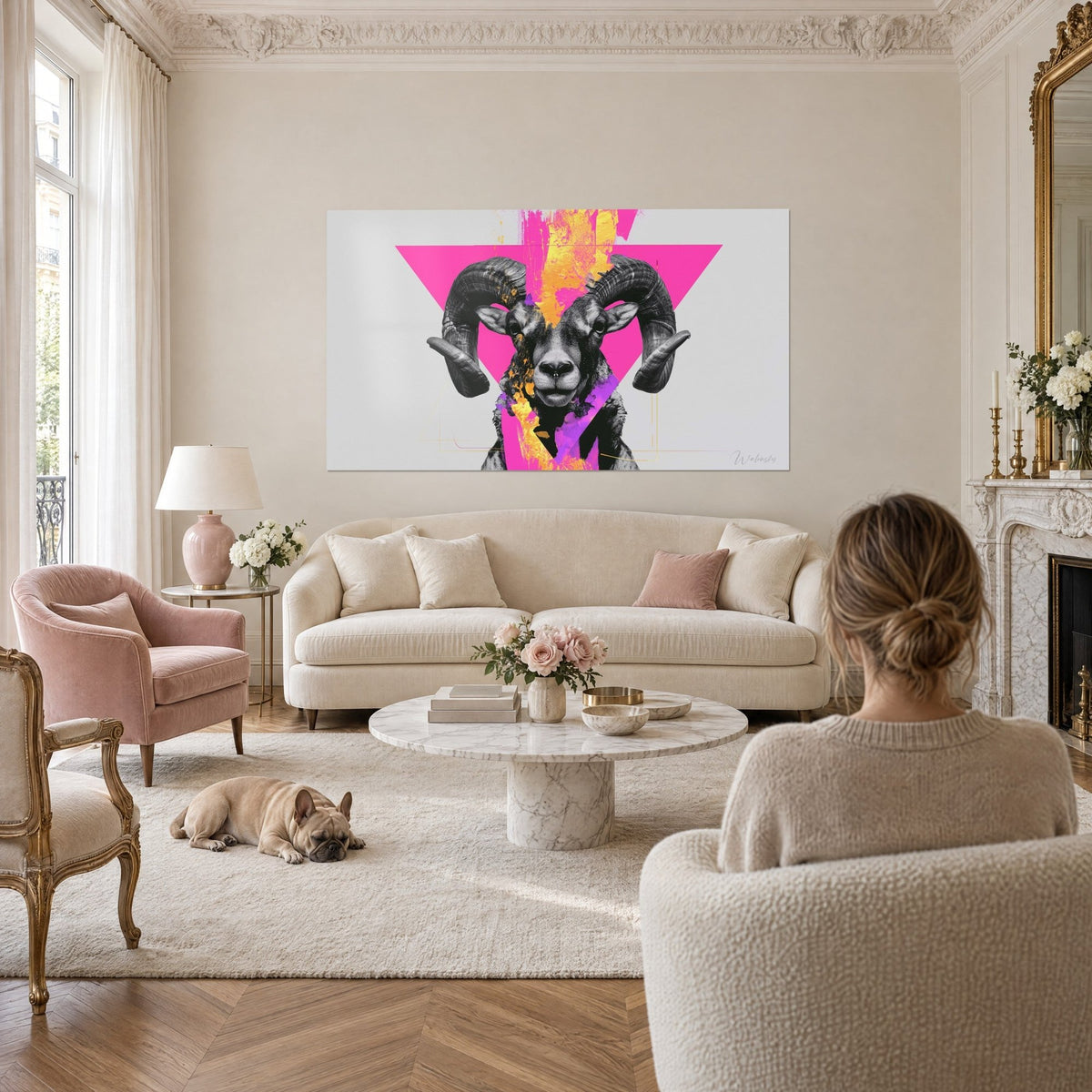 Tableau bélier aux cornes torsadées noir et blanc sur triangle fuchsia, au-dessus d'un canapé dans un salon lumineux