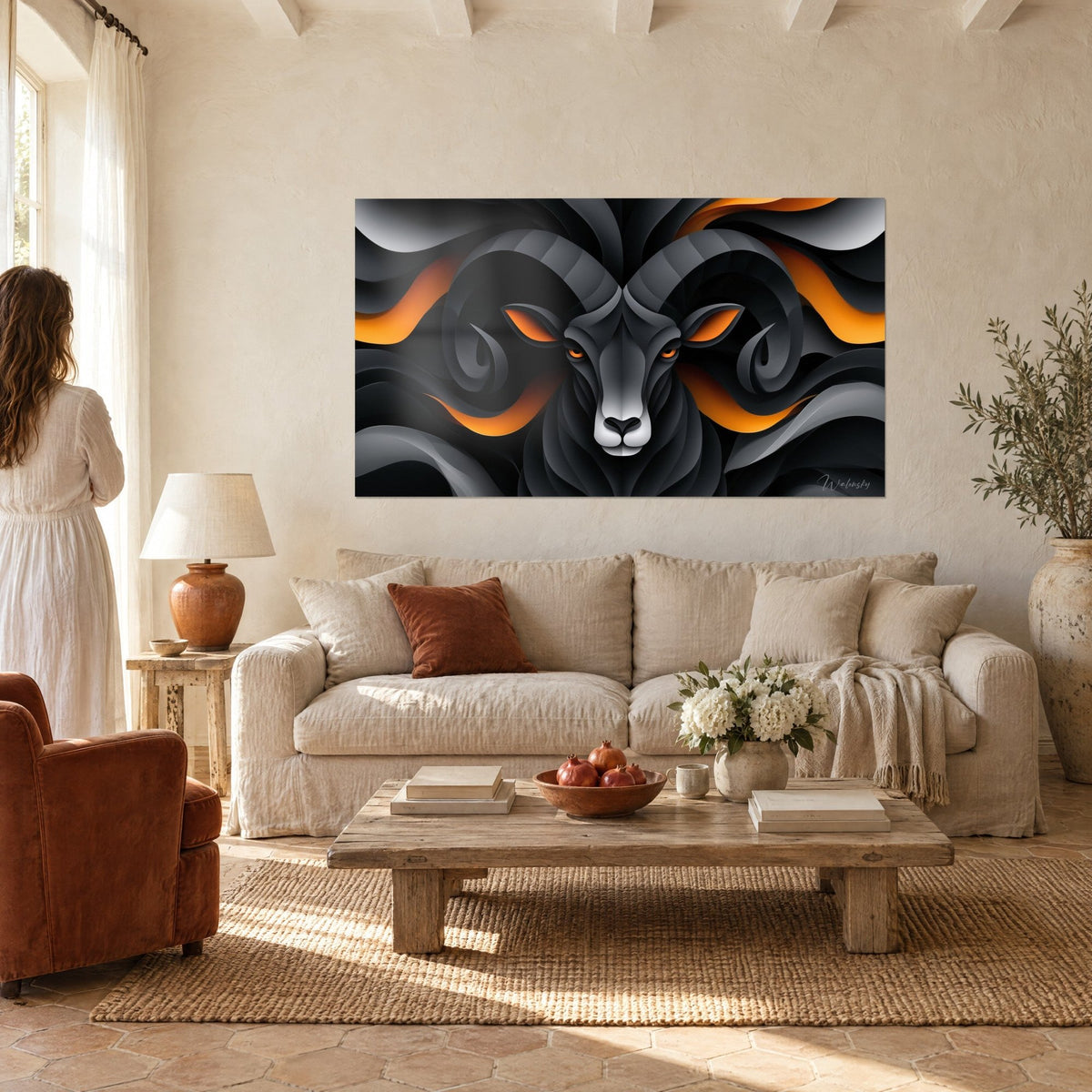 Quadro ariete nero dalle corna a spirale e occhi arancio incandescenti su fondo antracite e grigio, sopra un divano in un soggiorno luminoso