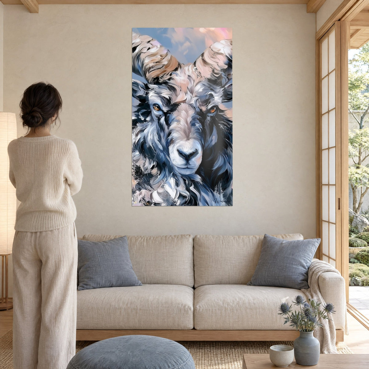 Quadro ariete con corna ritorte beige e rosate, vello blu ardesia, donna di spalle, sopra un divano in un soggiorno luminoso