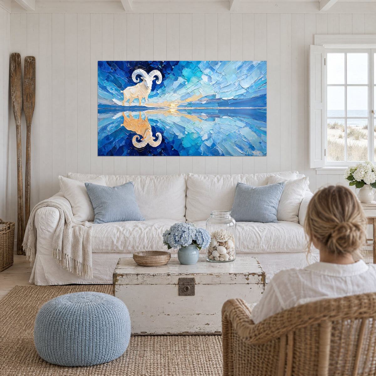 Tableau bélier ivoire aux cornes spiralées, reflet doré sur lac bleu cobalt, au-dessus d'un canapé dans un salon lumineux