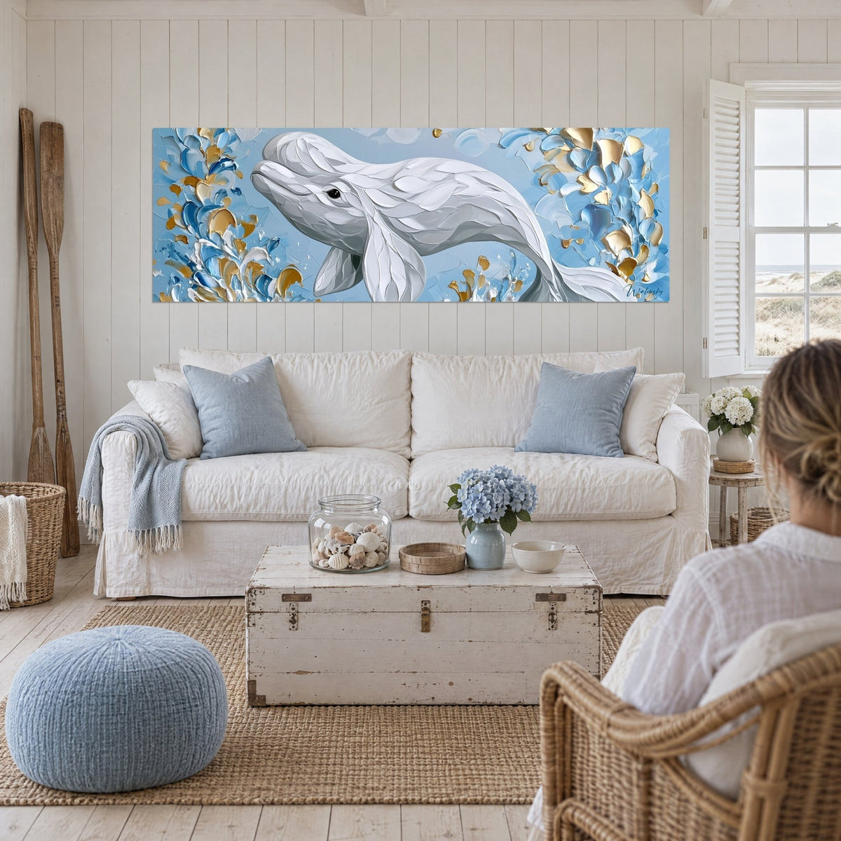Quadro di una balena beluga bianca con squame di colore in rilievo, sfondo azzurro pastello e oro, sopra un divano in un soggiorno luminoso