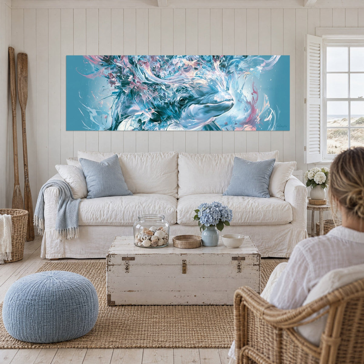 Tableau béluga au regard paisible, éclaboussures bleu sarcelle et rose poudré, au-dessus d'un canapé dans un salon lumineux