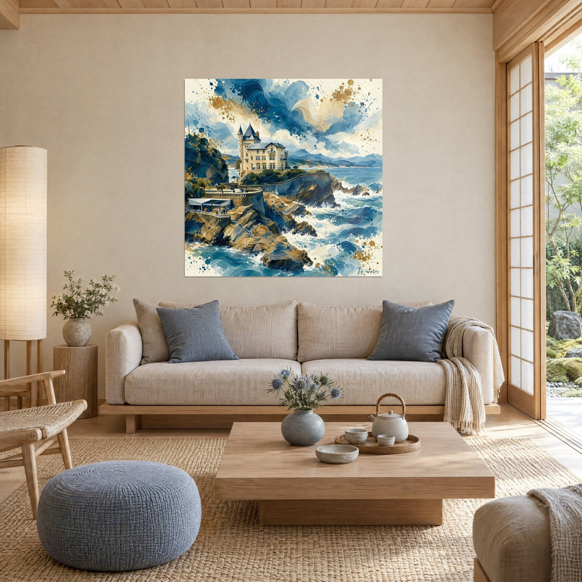 Wall art slate-turreted villa on a cliff, navy blue waves, gold spray, hung above a sofa in a bright living room