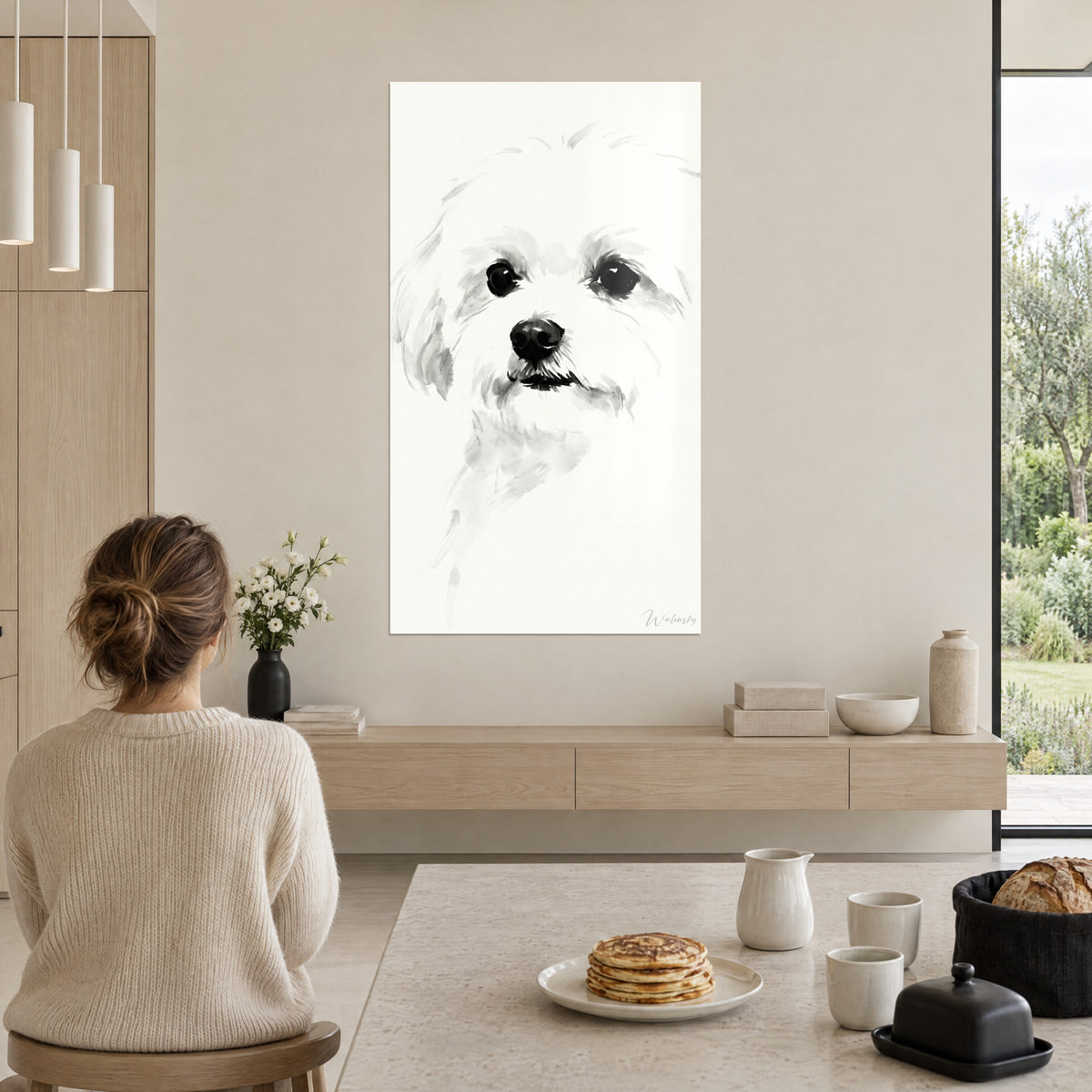 Wall art bichon face in black and white watercolour, shining eyes, woman seen from behind with a loose bun beside pancakes in a kitchen