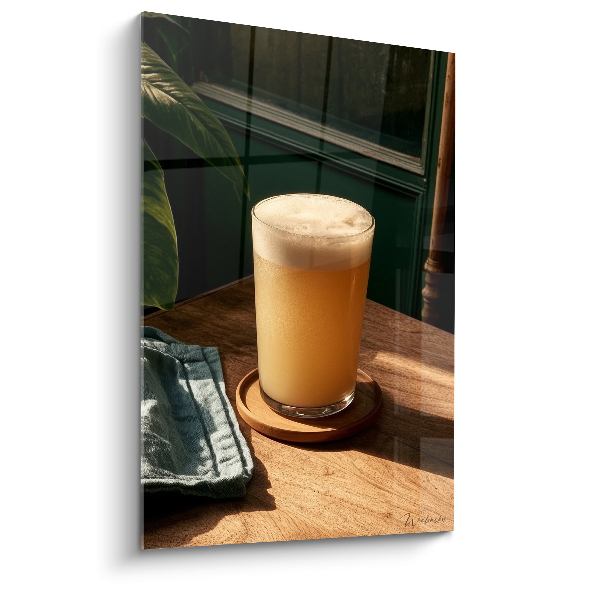 Bière ambrée mousse dorée dans un verre haut posé sur bois clair et vert