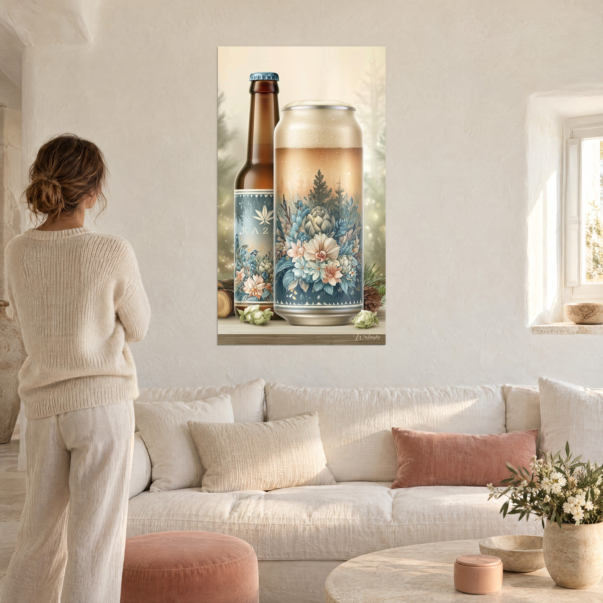 Cuadro de una lata de cerveza espumosa y botella marrón decoradas con flores azules y rosas, mujer de espaldas, encima de un sofá en un salón luminoso