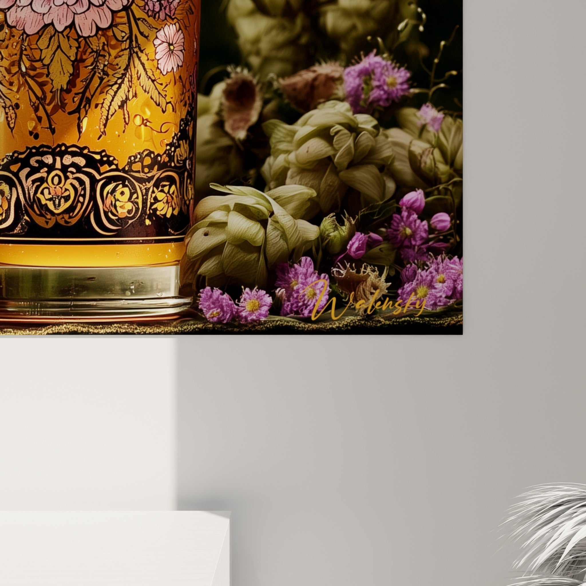 Détail des motifs floraux roses et noirs peints sur le verre à bière ambré et sa mousse crémeuse