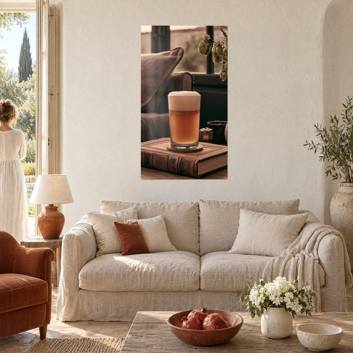 Wall art Amber beer with foamy head in a glass on a brown bound book, dried hops, two people seen from behind, above a sofa in a bright living room