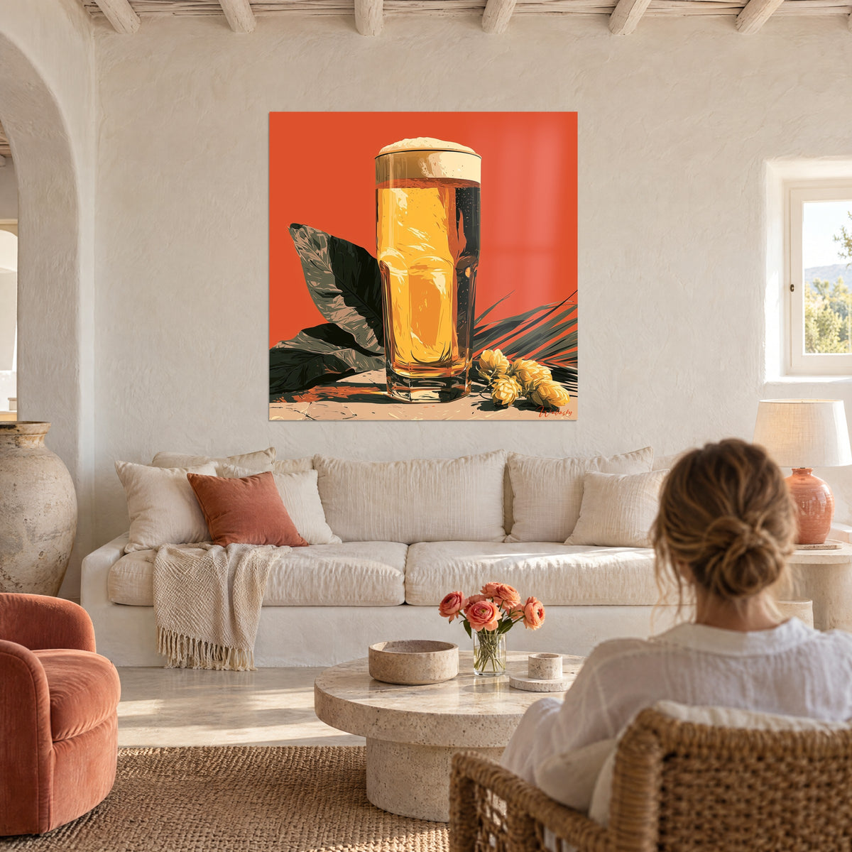 Tableau chope de bière dorée coiffée de mousse crémeuse sur fond corail, feuilles sombres, au-dessus d'un canapé dans un salon lumineux