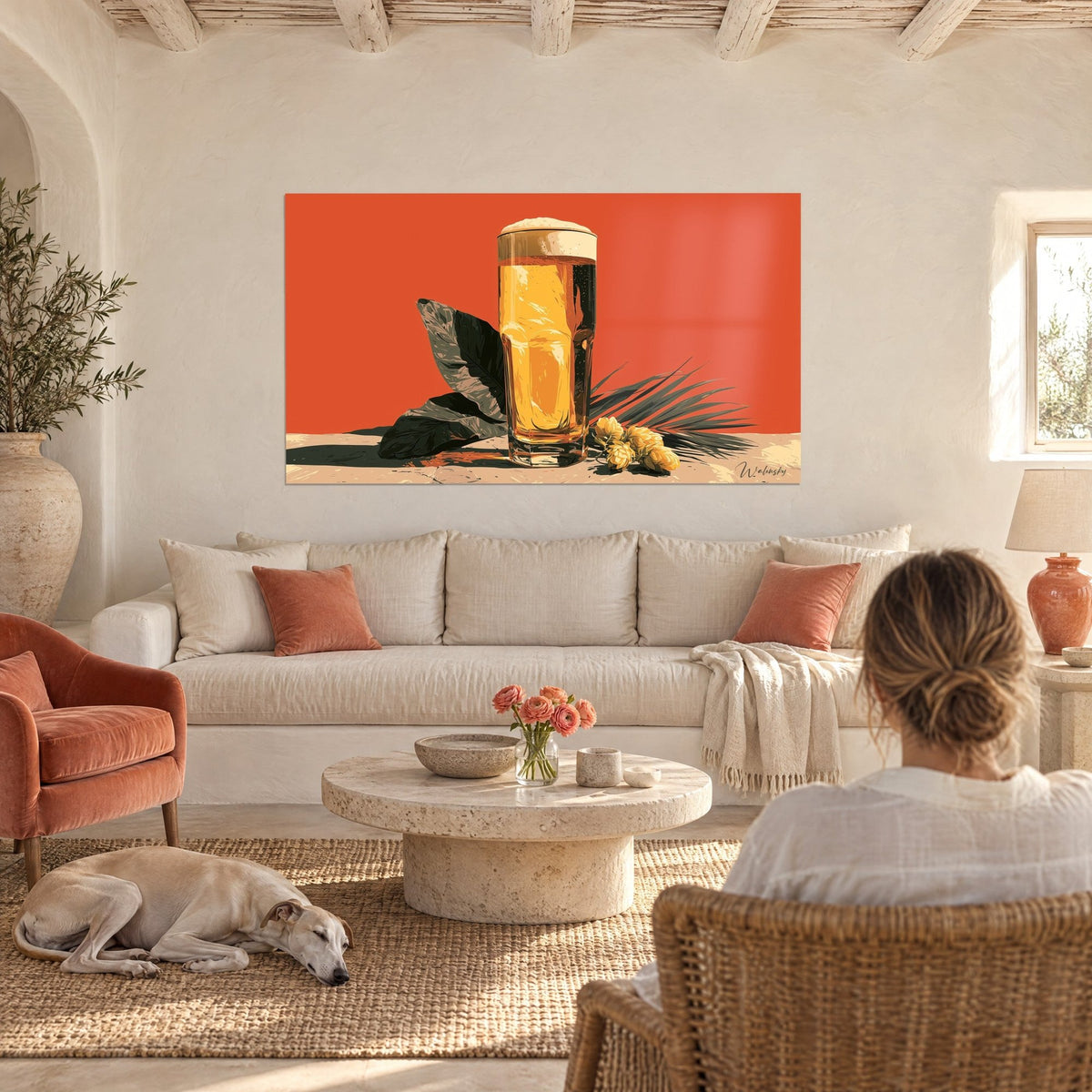 Gemälde Bierkrug mit blonder, schäumender Füllung, korallenroter Hintergrund und dunkelgrüne Blätter, über einem Sofa in einem hellen Wohnzimmer