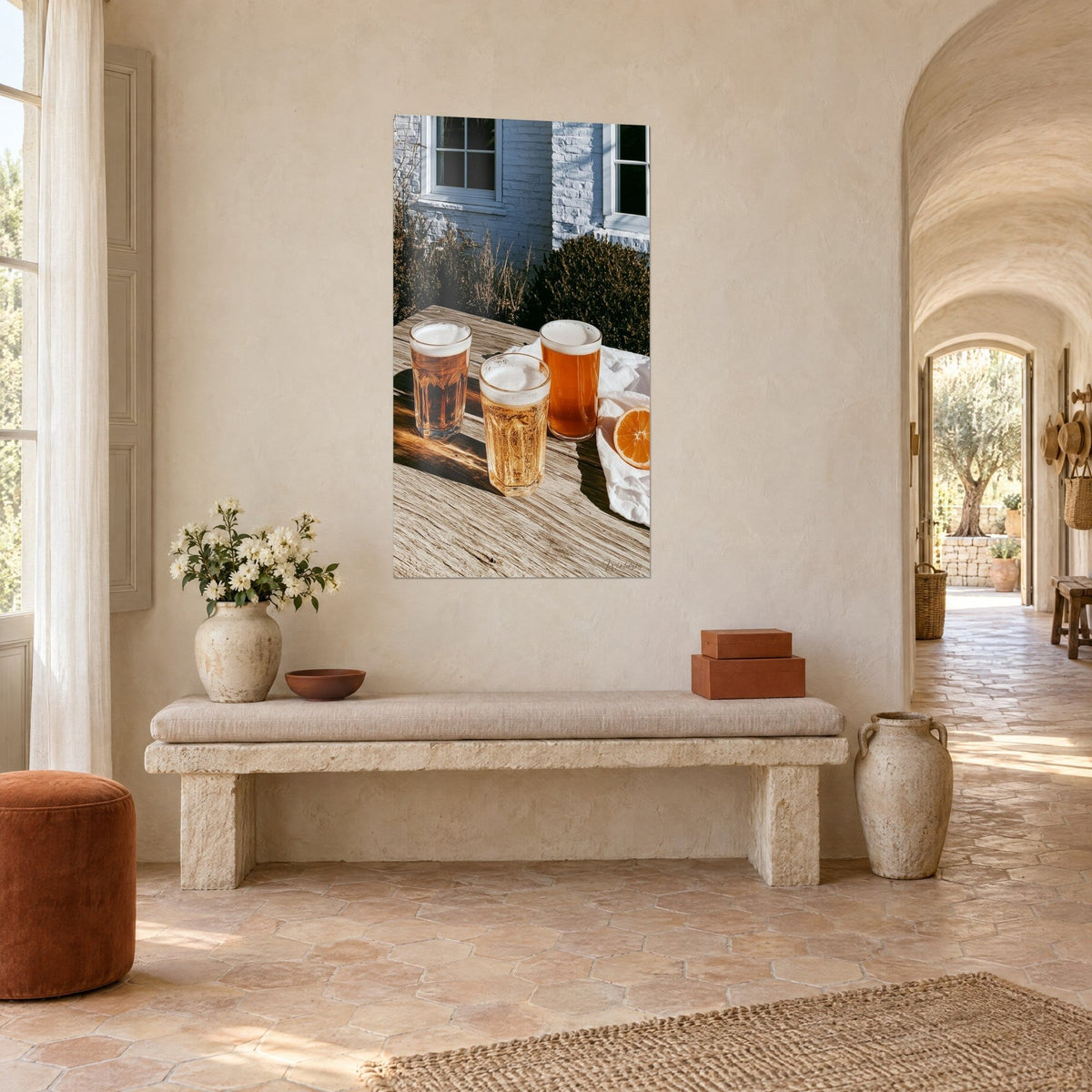 Quadro boccali di birra dorati e ambrati su tavolo patinato, fetta d'arancia, parete bianca, su una parete color crema in un casolare provenzale, vista a tre quarti