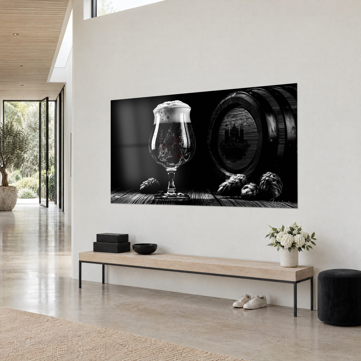 Quadro tulipano di birra scura coronato da schiuma bianca, botte cerchiata e coni di luppolo grigi, sfondo nero profondo, parete color crema e panca in legno