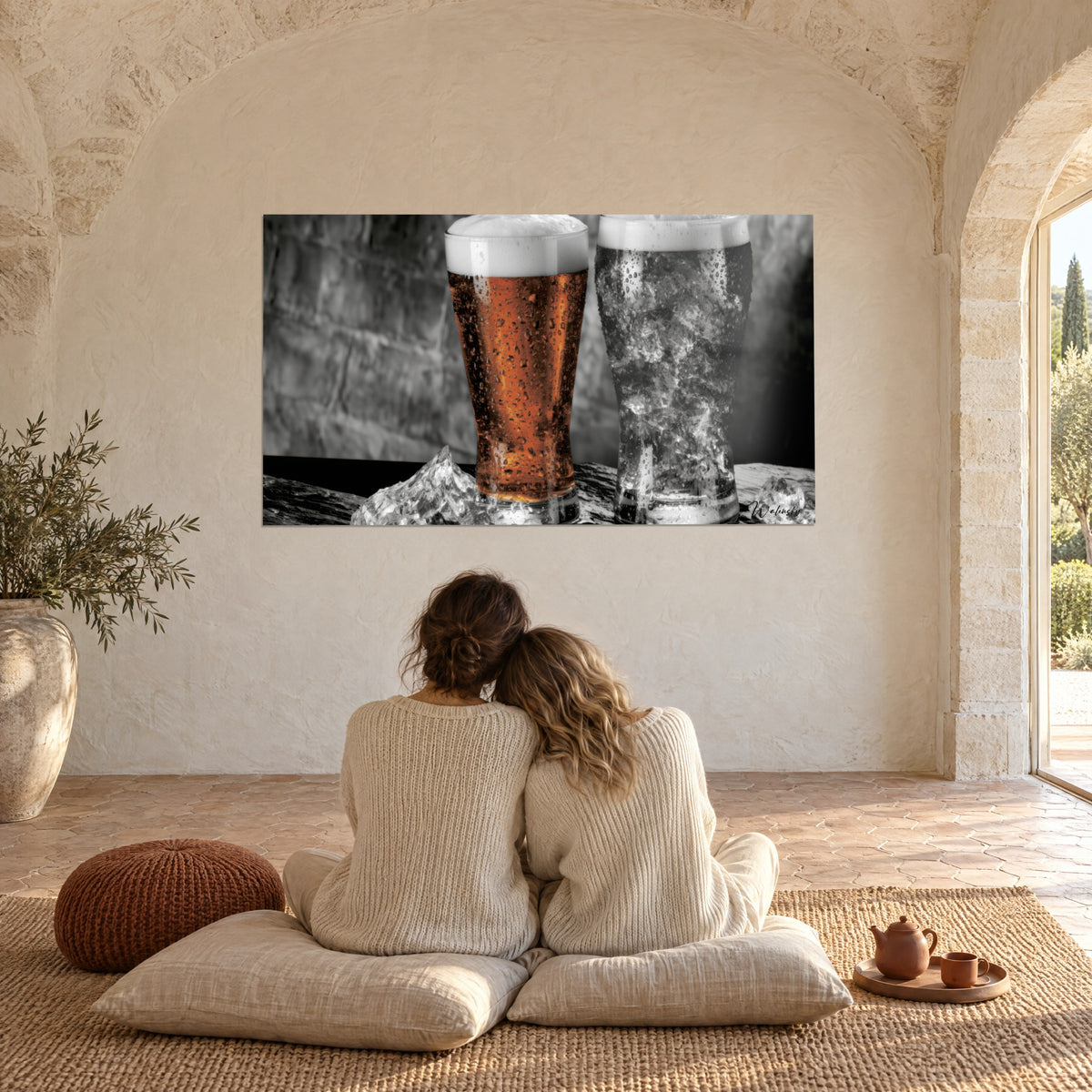 Tableau mousse neigeuse sur bière cuivrée, verre voisin rempli de glace grise et condensation, face à un couple assis sur des coussins