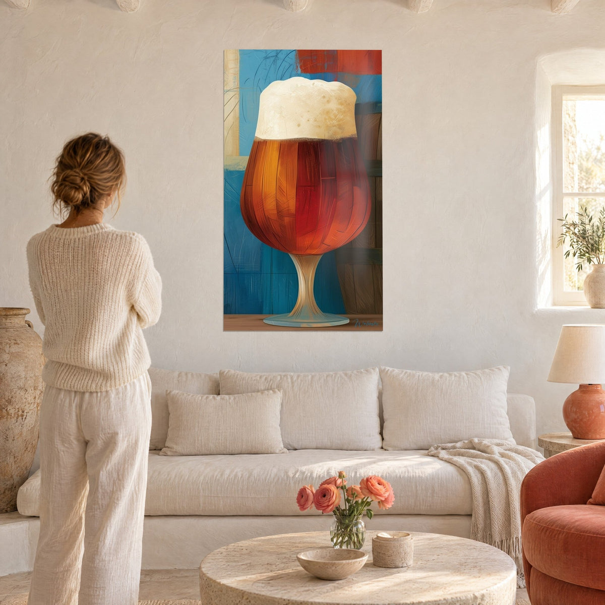 Gemälde mit bernsteinfarbenem Bierkrug mit cremiger Schaumkrone, blauer und roter Hintergrund, Frau von hinten, über einem Sofa in einem hellen Wohnzimmer aufgehängt