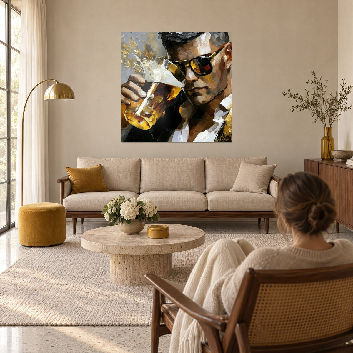 Tableau homme en lunettes noires buvant une bière dorée, touches de blanc et d'ocre, au-dessus d'un canapé dans un salon lumineux