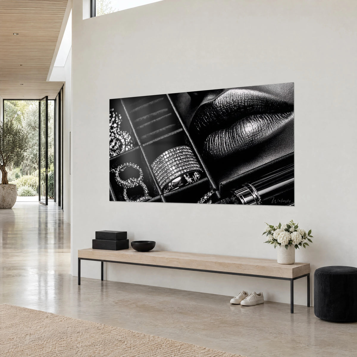 Cuadro monocromo de joyero, anillo engastado con cristales plateados y labios negros texturizados, vista de tres cuartos sobre una pared blanca