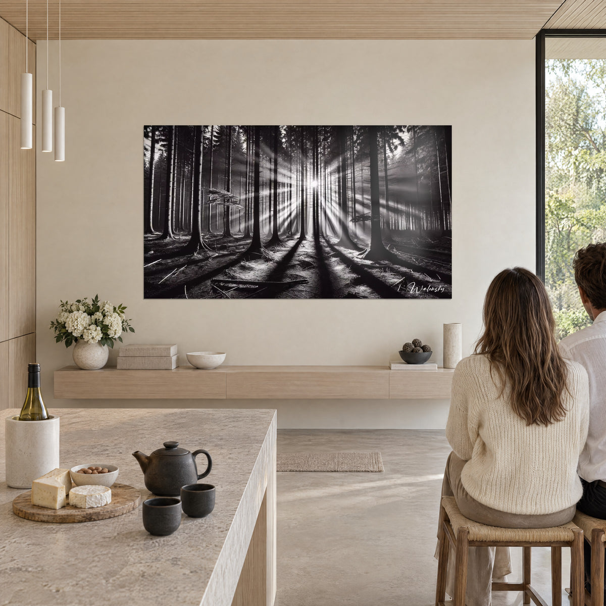 Quadro luce filtrata tra abeti, lunghe ombre nere su pavimento grigio, parete bianca, legno chiaro, per un momento di vita in cucina aperta