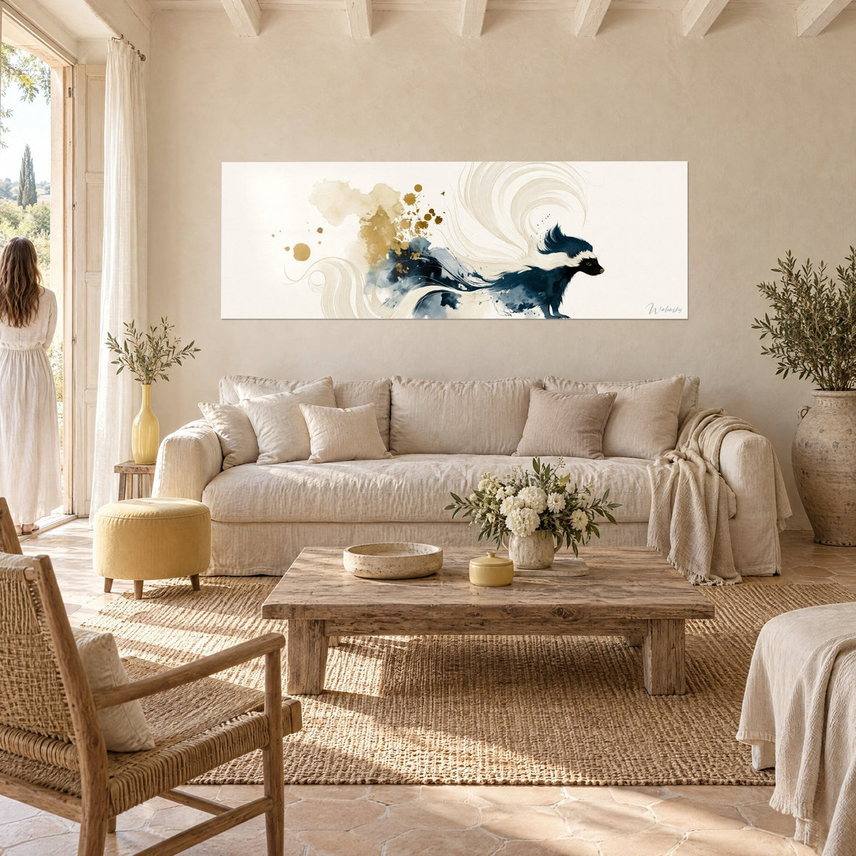 Wall art navy skunk with a cream stripe trailing into gold splashes, woman seen from behind, above a sofa in a bright living room