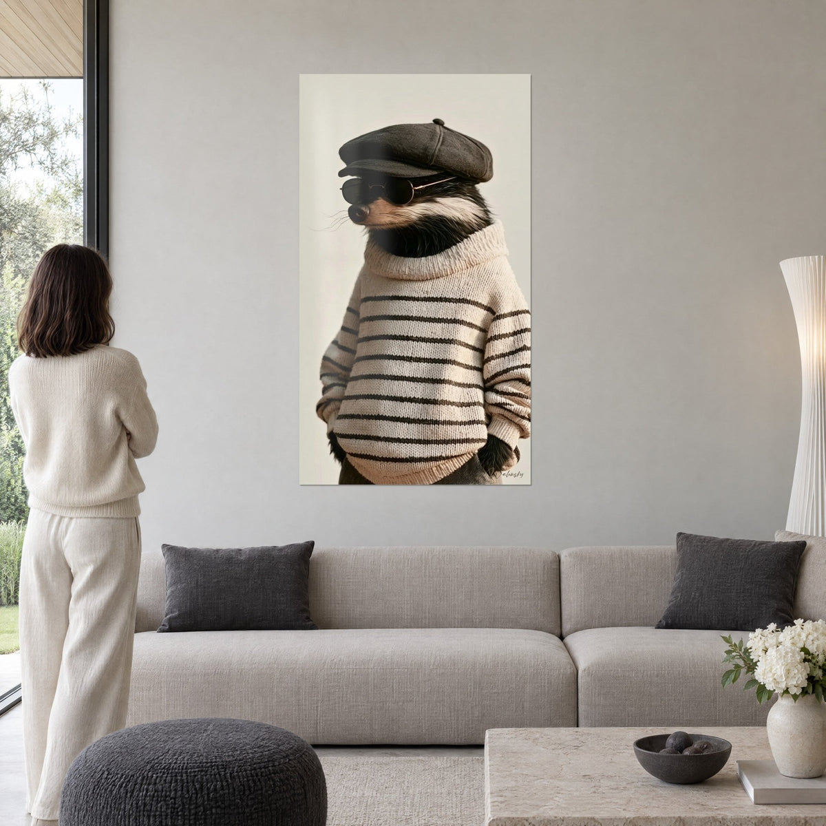 Tableau blaireau en pull marin crème, casquette grise et lunettes rondes sur fond beige, au-dessus d'un canapé dans un salon lumineux