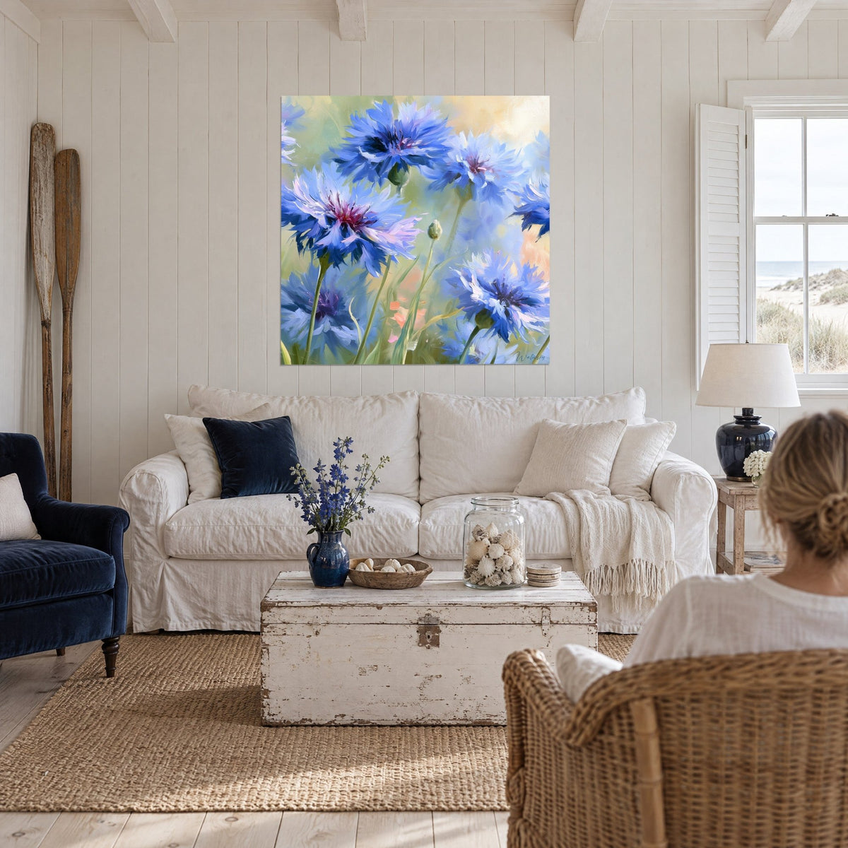Tableau bleuets bleu cobalt et lilas sur fond vert tendre, au-dessus d'un canapé dans un salon lumineux