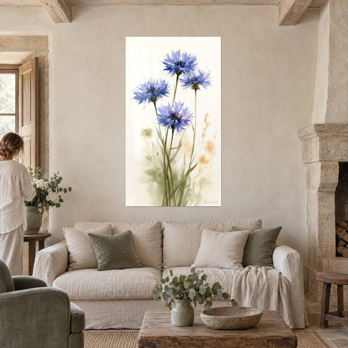 Tableau bleuets en aquarelle, quatre fleurs bleu violet sur fond ivoire, personne de dos, au-dessus d'un canapé dans un salon lumineux
