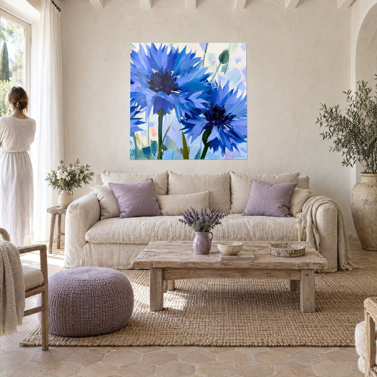 Schilderij korenbloemen in stralend kobaltblauw met puntige bloemblaadjes, donkerviolette kern, crèmekleurige achtergrond, boven een bank in een lichte woonkamer