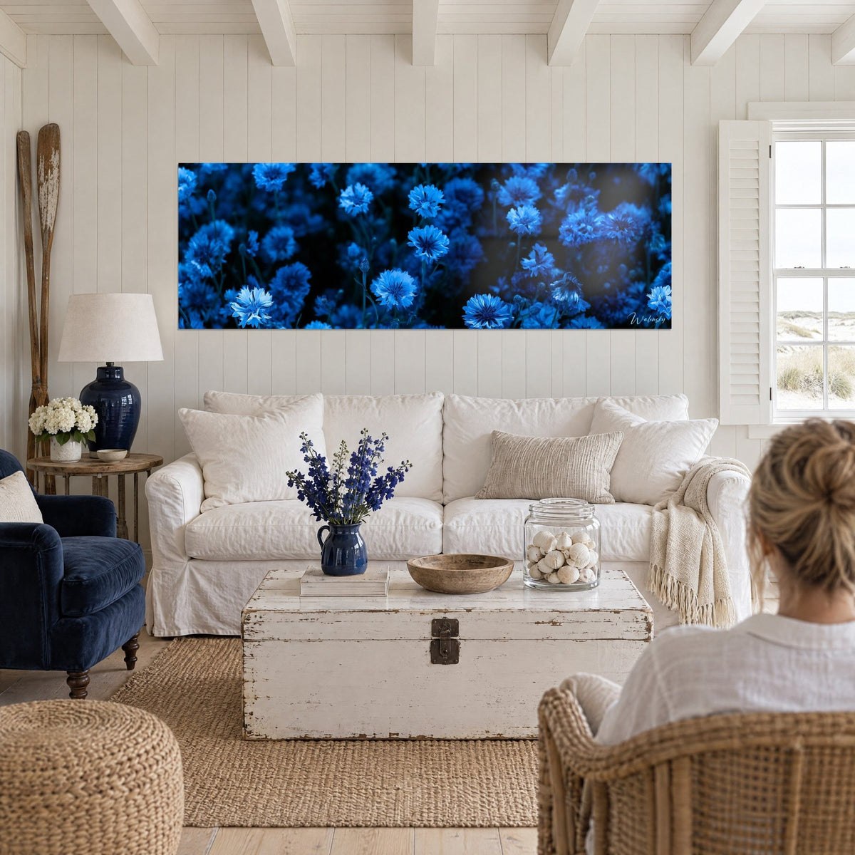 Quadro campo di fiordalisi notturni, fiori blu elettrico su fondo nero profondo, sopra un divano in un soggiorno luminoso