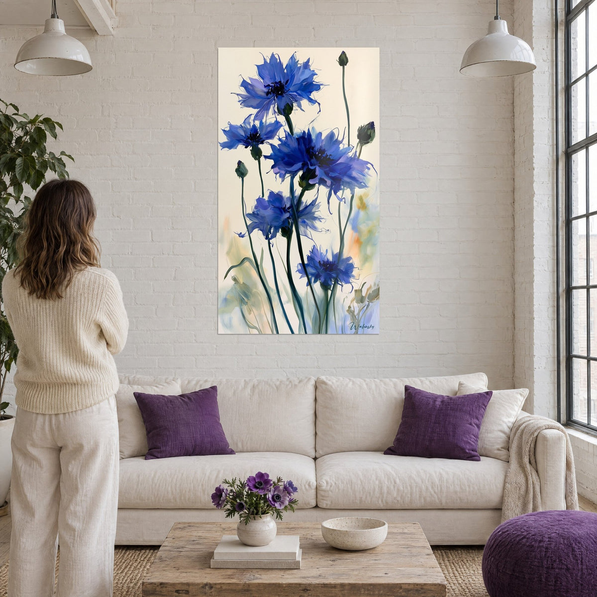 Tableau bleuets bleu cobalt et violet aux pétales effilochés sur fond ivoire, au-dessus d'un canapé dans un salon lumineux