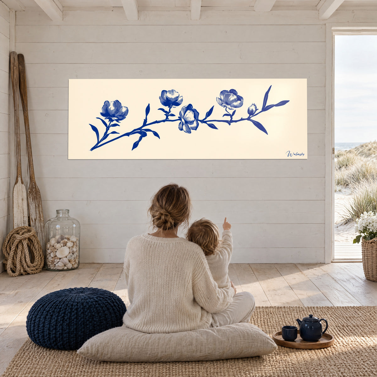 Schilderij van een tak met vijf marineblauwe bloemen op ivoorkleurige achtergrond, witte muur in een open ruimte met uitzicht op de duinen, moeder en kind van achteren