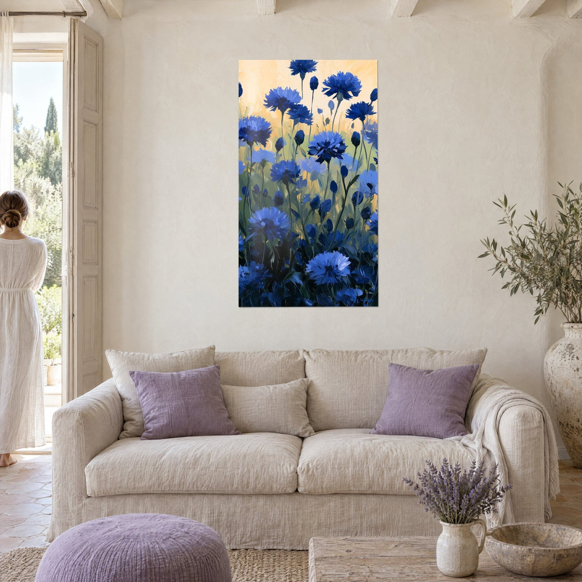 Tableau champ de bleuets indigo sur fond pêche, tiges dressées, au-dessus d'un canapé dans un salon lumineux