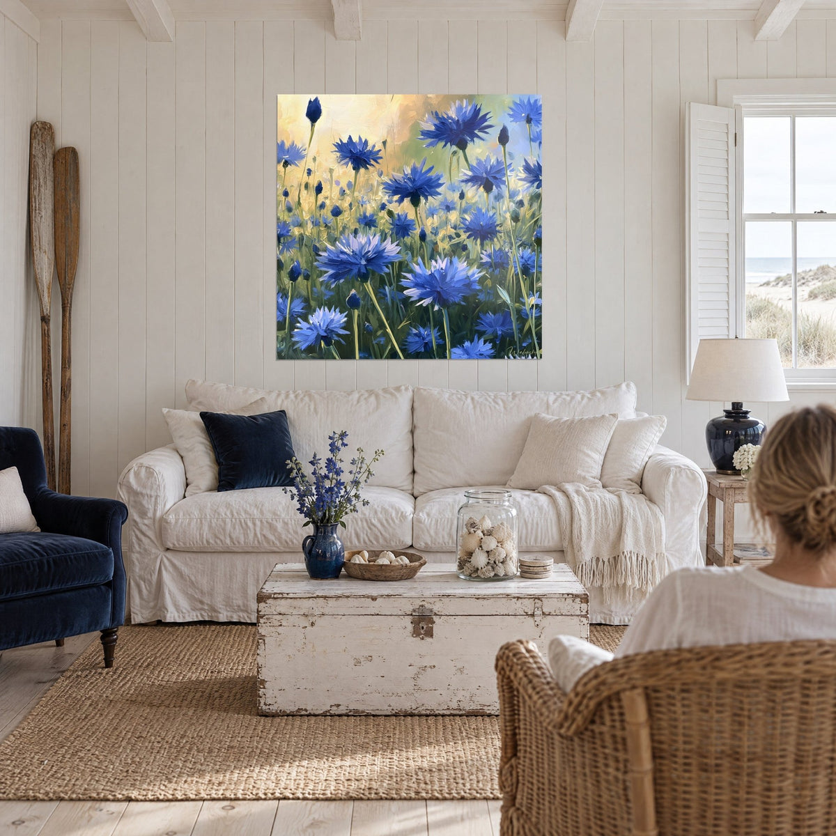 Tableau fleurs de bleuet bleu cobalt sur fond ocre doré, coups de pinceau épais, au-dessus d'un canapé dans un salon lumineux