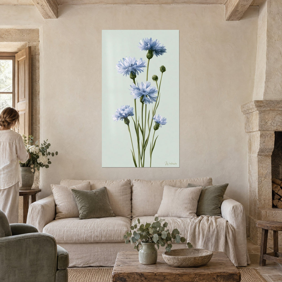 Tableau bleuets bleu pâle sur tiges vert olive, fond céladon, femme de dos, au-dessus d'un canapé dans un salon lumineux